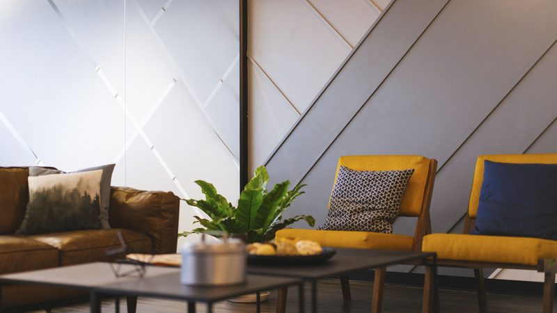 A living room with a brown leather sofa, two mustard armchairs, a coffee table and a plant